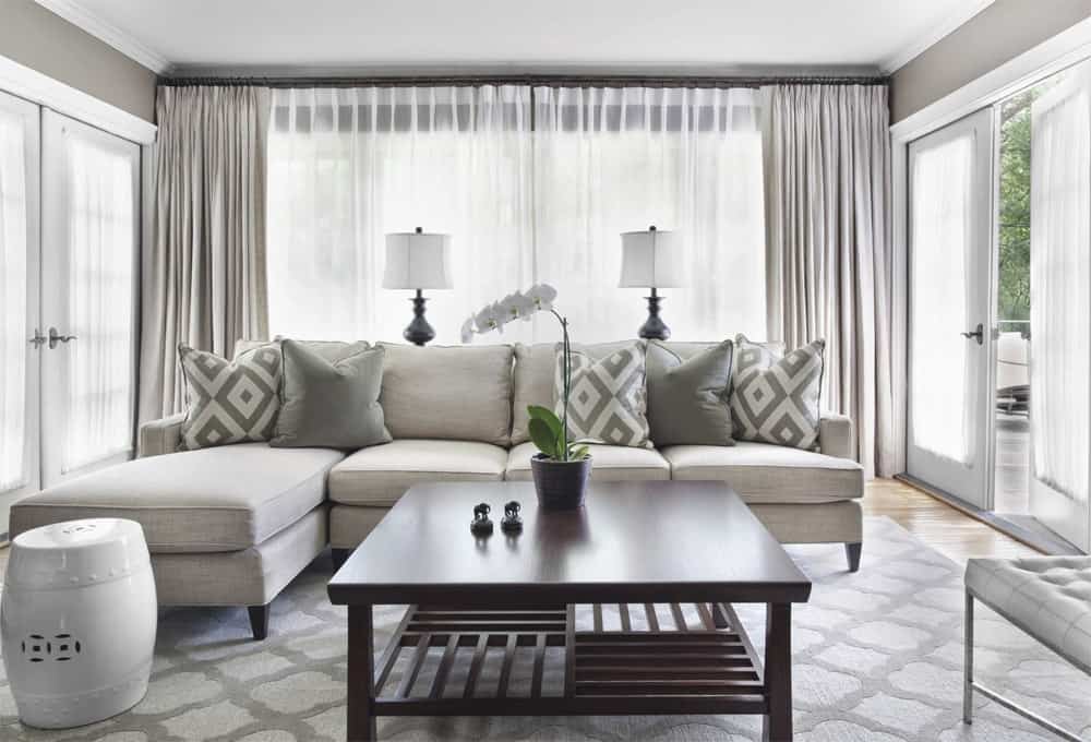 sivá rohová sedačka v obývačke so závesmi